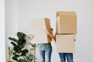 couple carrying cardboard boxes in living room couple carrying cardboard boxes in living room